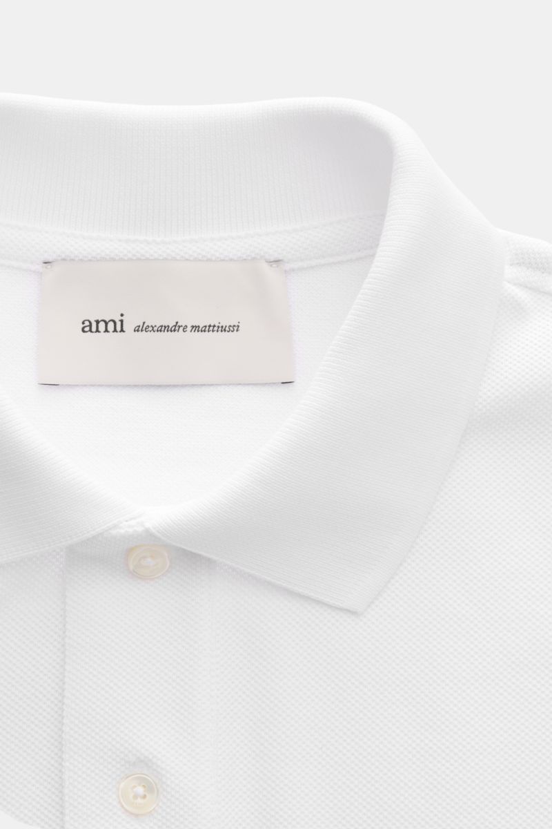 Nahaufnahme des weißen Ami Paris Poloshirts aus Baumwoll-Piqué, slim fit, mit Polokragen, Zwei-Knopf-Leiste und 'A'-Stitching auf der Brust.