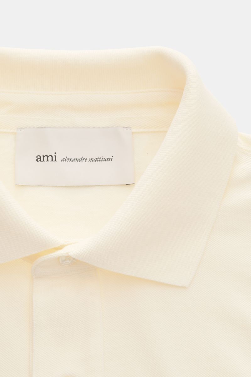 Close-up front view of Ami Paris Polo shirt cream showing signature collar, three-button placket, and textured piqué cotton fabric with logo stitching. 

Description: A casual classic among polo shirts: This piqué model in pure cotton with three-dimens