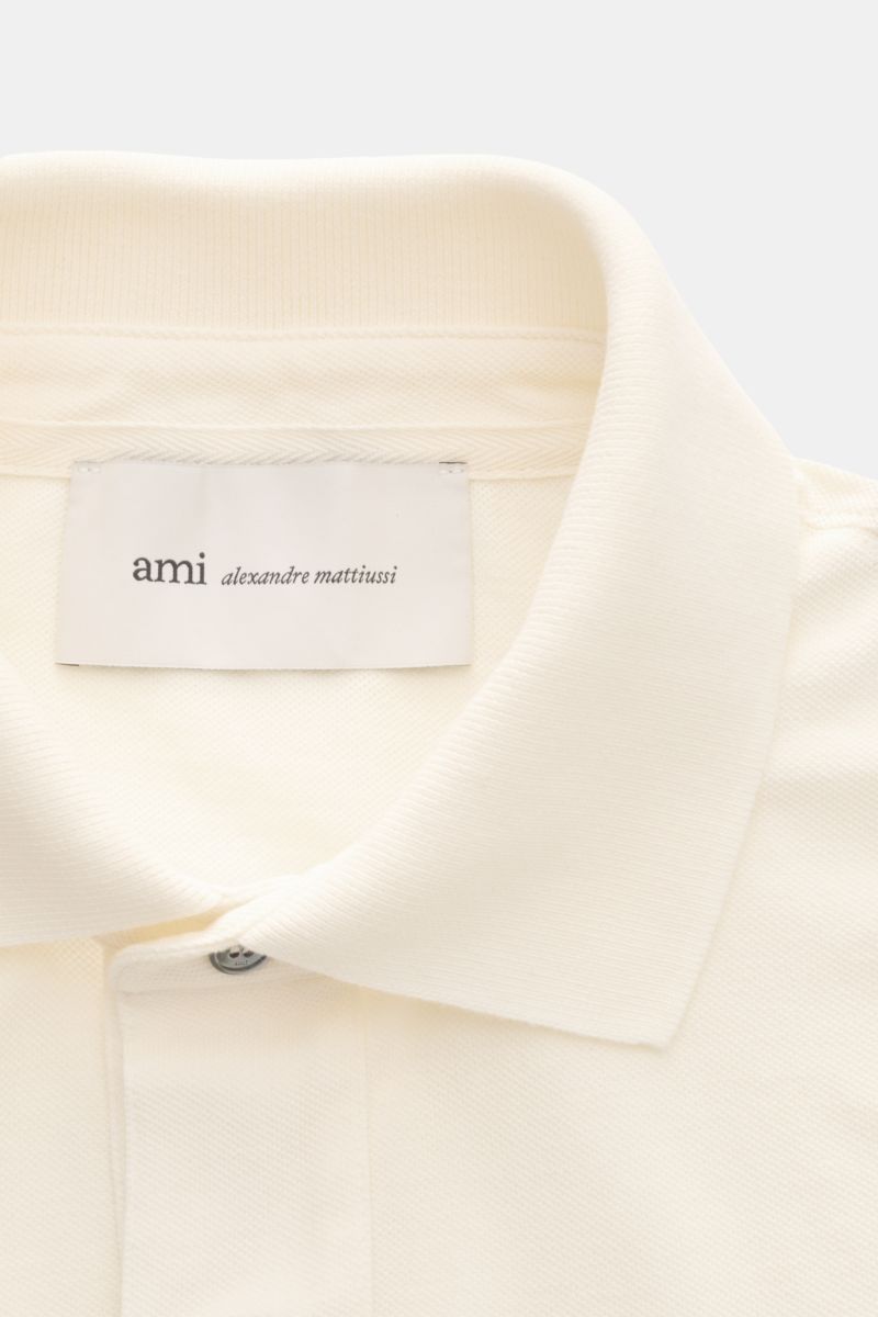 Nahaufnahme des cremefarbenen Ami Paris Poloshirts 'Boxy Fit' mit typischem Polokragen, Drei-Knopf-Leiste und feiner Piqué-Struktur aus reiner Baumwolle.