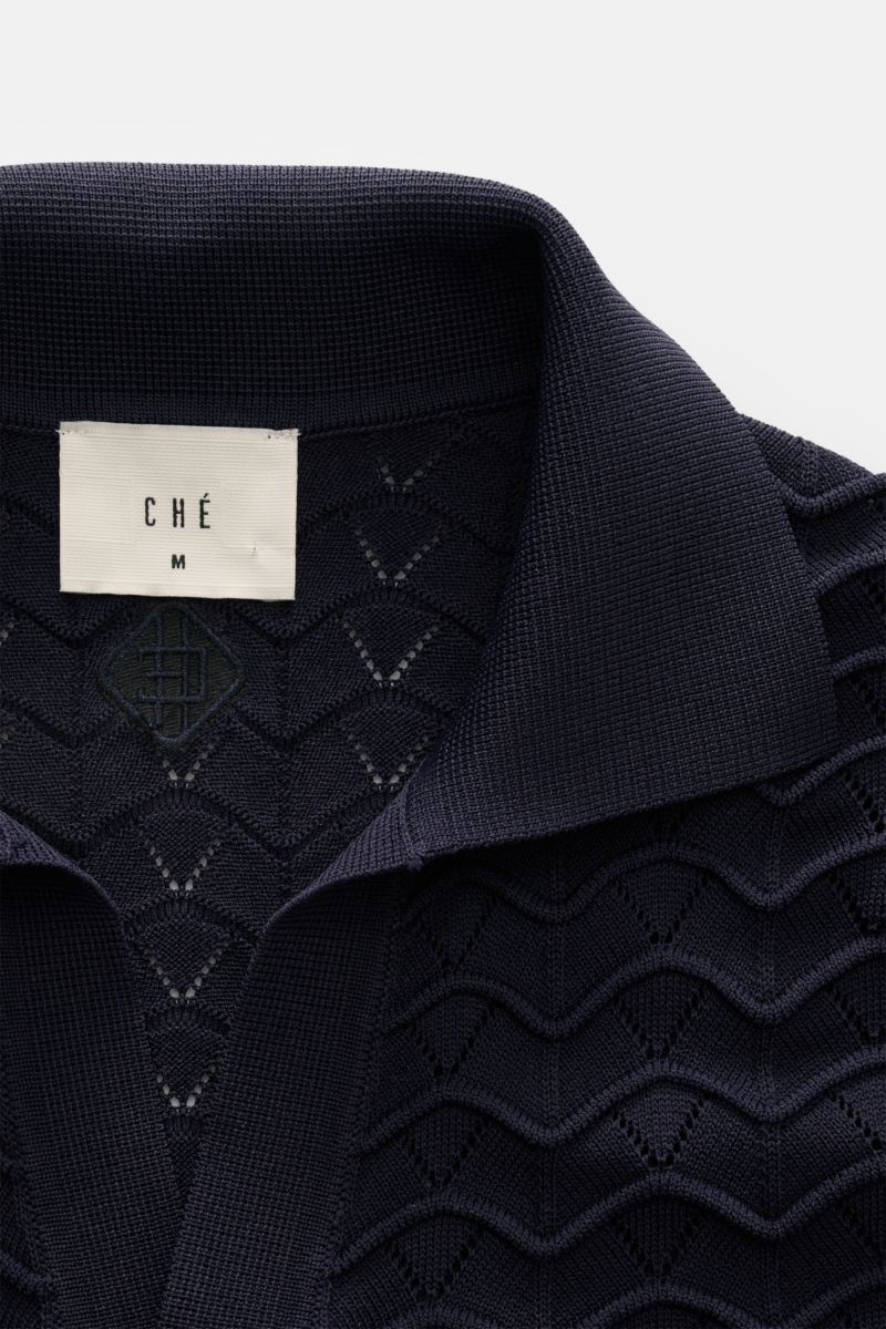 Close-up top-down view of the navy Ché Kurzarm-Strickpolo 'Ripple' showing its classic polo collar and textured airy knit fabric.

Lässige Beach Vibes: Das Strickpolo von CHÉ garantiert entspannte Looks für warme Tage.

Mix aus Viskose und 