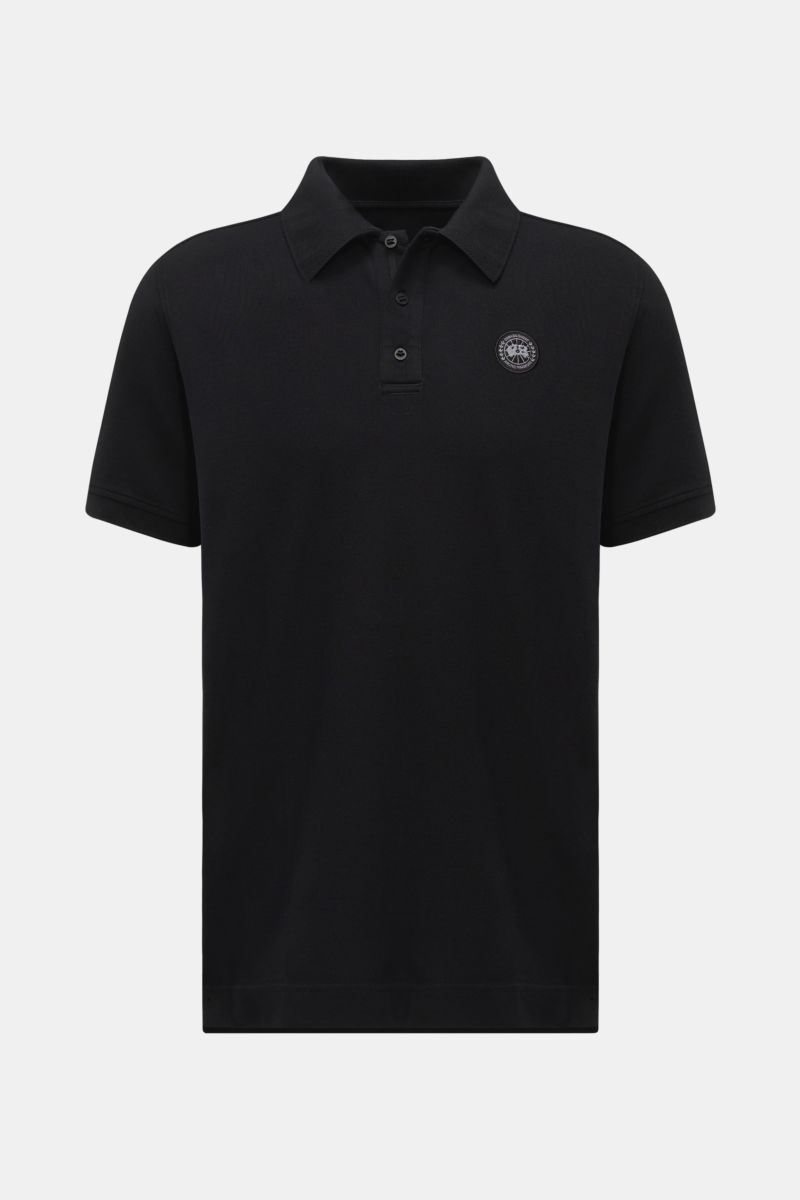 Front view of Canada Goose Poloshirt schwarz, a classic black polo shirt made of pure cotton piqué with a structured feel, three-button placket, chest patch, flexible cuffs, side slits, and slightly extended back.

Description: Das klassische Poloshirt