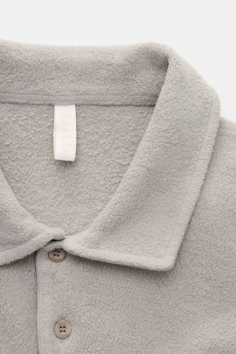 Nahaufnahme des grauen 04651/ A trip in a bag Fleece Langarm-Poloshirts aus reiner Baumwolle, softem Griff, garment dyed, Regular Fit, mit typischem Polokragen, Drei-Knopf-Leiste, kleinem Weblabel in der Seitennaht und kurzen Saumschlitzen, aus schräger P