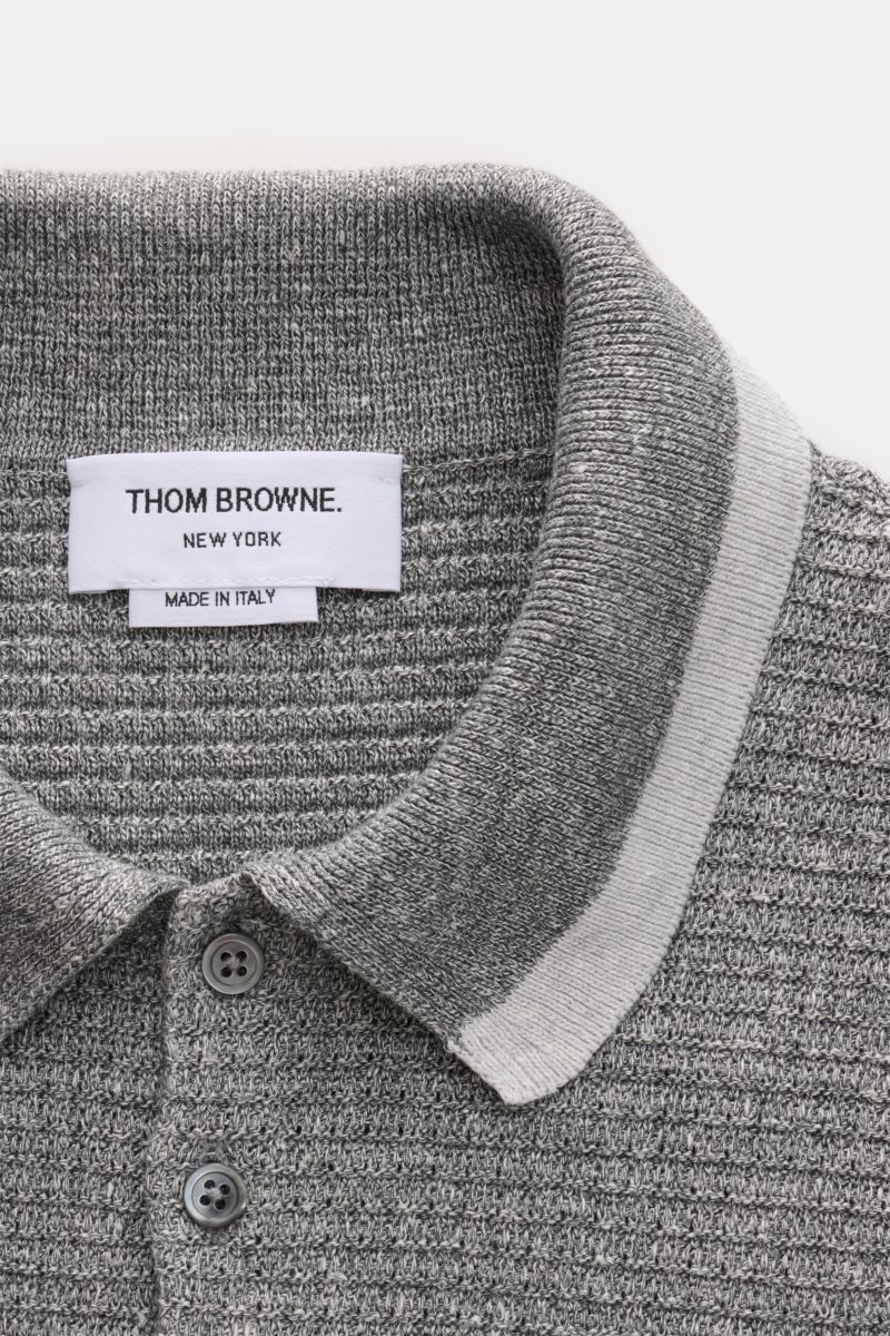 Close-up top-down view of the grey melange Thom Browne Strickpolo, showcasing its knitted collar, five-button placket, and textured knit pattern.