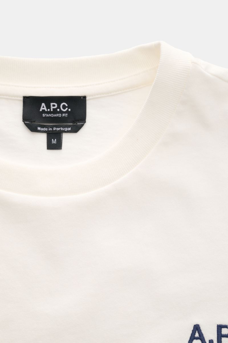 A close-up front view of the A.P.C. Crew neck T-shirt 'Standard Rue Madame' off-white, showing the crew neck collar and black label with logo. Clean, cool, A.P.C. – the T-shirt 'Standard Rue Madame' is the epitome of French understatement. In soft cott