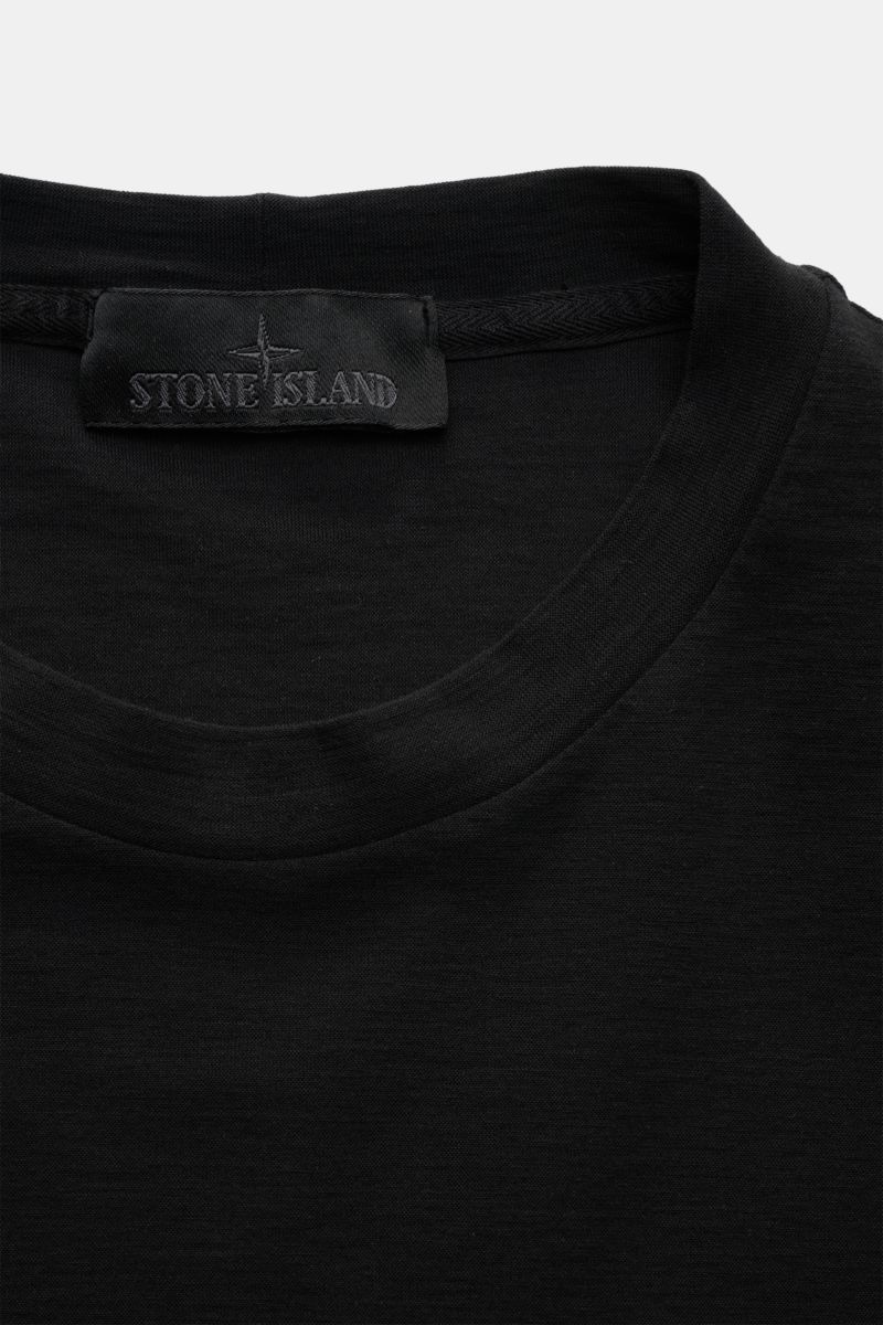 Close-up front view of Stone Island Rundhals-T-Shirt 'Ghost Piece' schwarz, showing the elastic cotton jersey fabric and tonal STONE ISLAND label on the chest.

Description: STONE ISLAND bietet mit dem Rundhals-T-Shirt aus elastischem Baumwolljersey mi