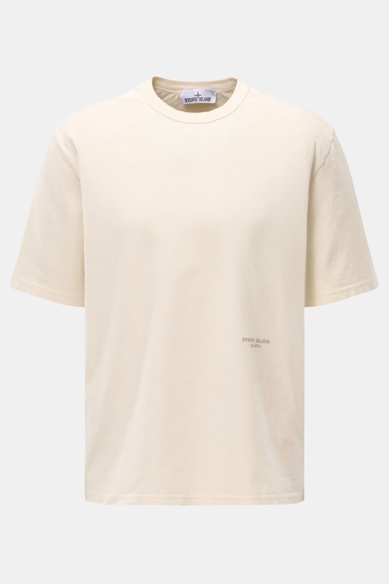 Stone Island Rundhals-T-Shirt 'Marina' creme shown from the front, oversized fit with a soft, heavy cotton fabric, round neckline, contrast ribbed shoulder detail, and subtle logo print on the front. Legeres Urlaubs-Essential: Das T-Shirt aus der STONE
