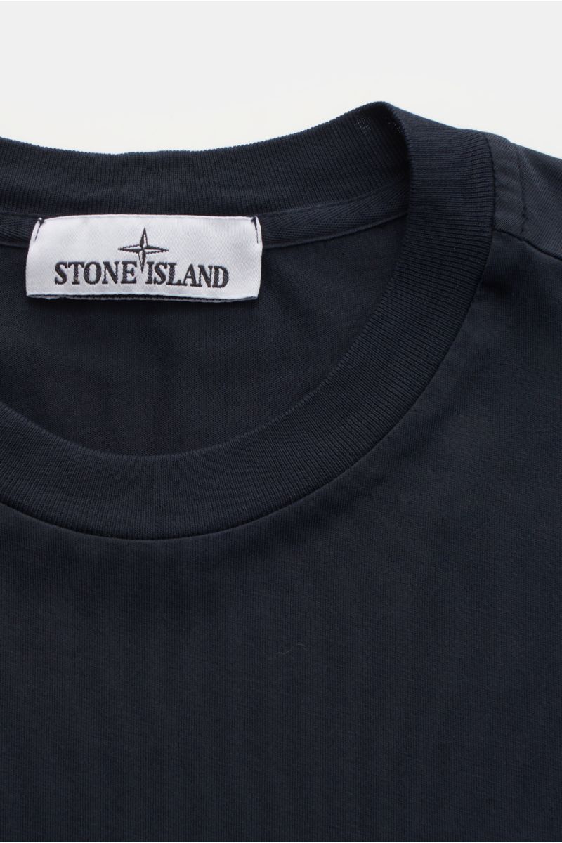 Nahaufnahme des Stone Island T-Shirts 'Basic Cotton' navy mit Rundhalsausschnitt, Weblabel auf der Brust, Slim Fit und weichem Griff aus reiner Baumwolle. Zeitloses Basic Piece für legere Freizeitlooks.