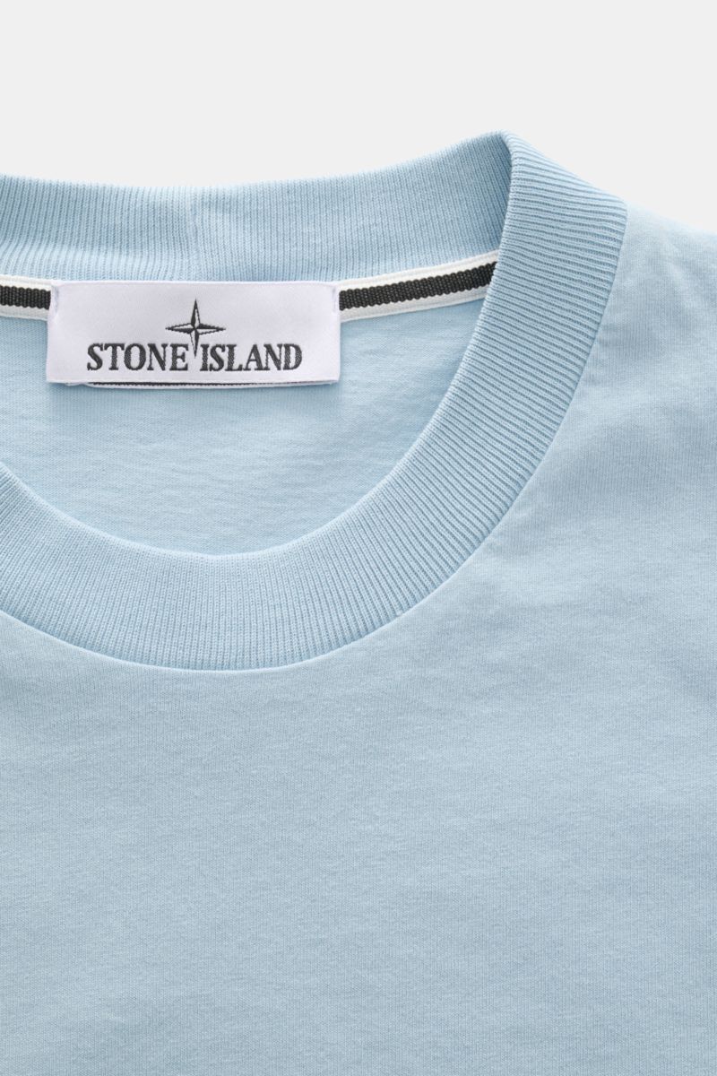 Stone Island Rundhals-T-Shirt hellblau in Nahaufnahme von oben, weicher Baumwoll-Jersey, Regular Fit, Front- und Rückenprint sichtbar.