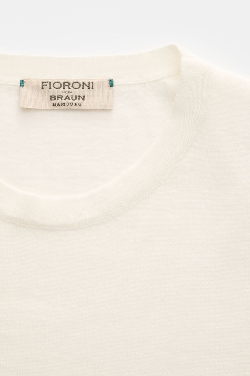 Close-up front view of Fioroni Rundhals-T-Shirt offwhite showing fine knit, round neckline, and label. Für den gediegenen Auftritt im Frühling sorgt dieses fein gestrickte T-Shirt von FIORINI, welches aus reiner Baumwolle gefertigt wurde und mit edlen han