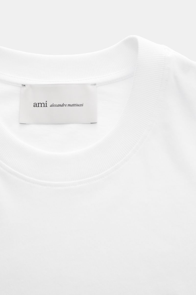 Close-up front view of Ami Paris Crew neck T-shirt white, showing the ribbed crew neck and label inside collar.

Classic jersey basic by French label AMI PARIS: This crew neck T-shirt is made of pure cotton and the small heart stitching on the chest ma