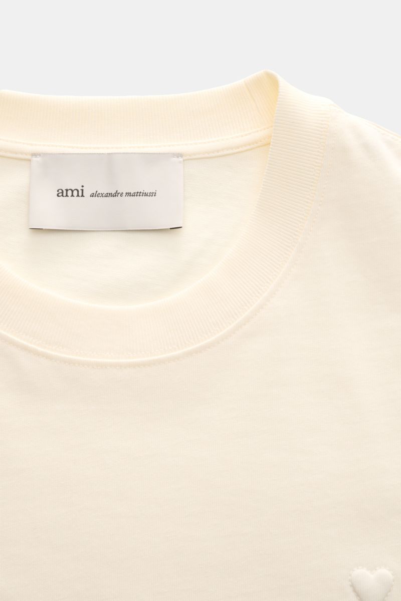 Ami Paris Rundhals-T-Shirt creme, Nahaufnahme von Rundhalsausschnitt, Jersey aus Baumwolle, abgesteppte Herz-Logo und Label innen.