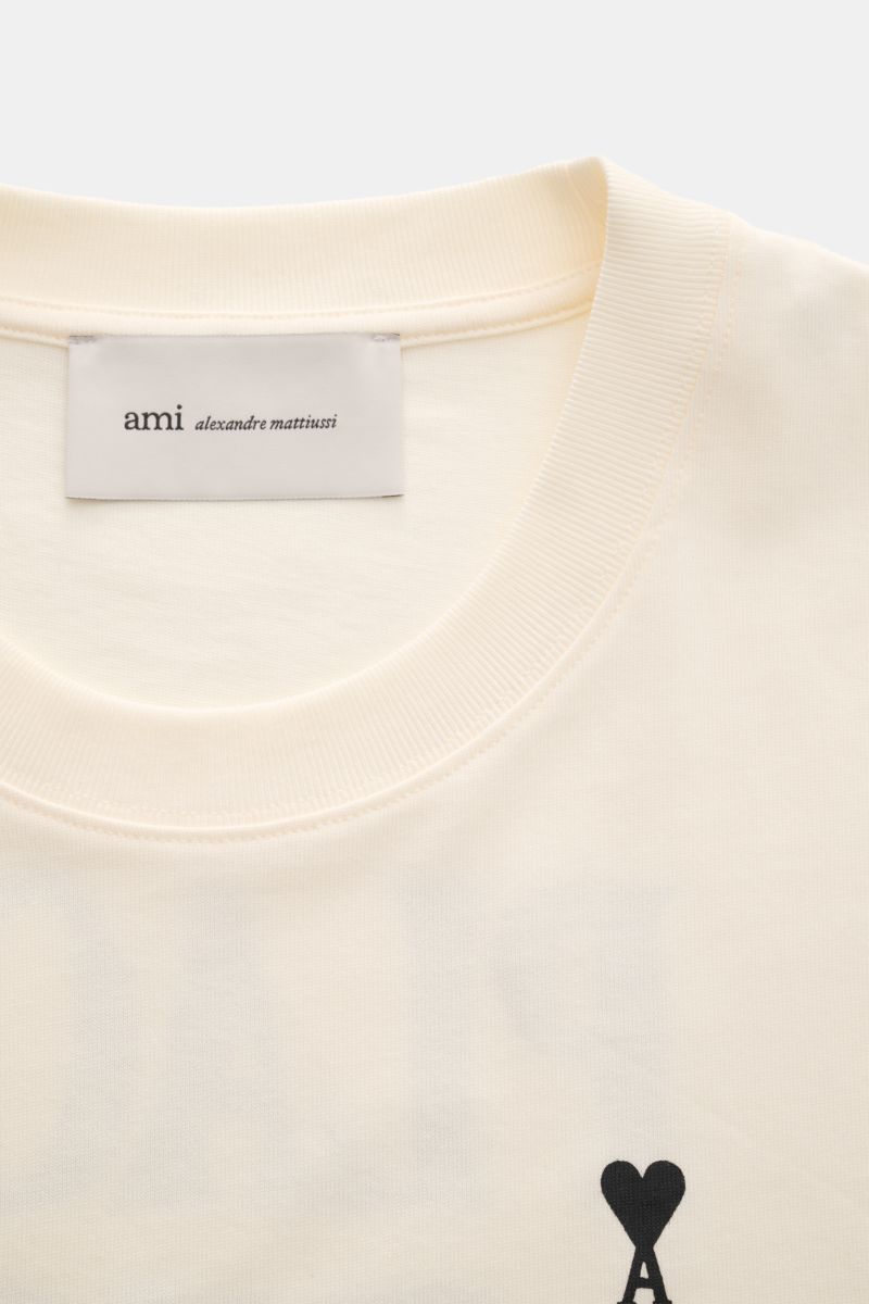 Ami Paris Rundhals-T-Shirt creme shown from a top front view, made of pure organic cotton jersey with a soft feel, regular fit, round neckline, tonal heart-stitch logo on the chest, and tonal AMI stitching on the back. Monochromes Jersey-Basic vom französ