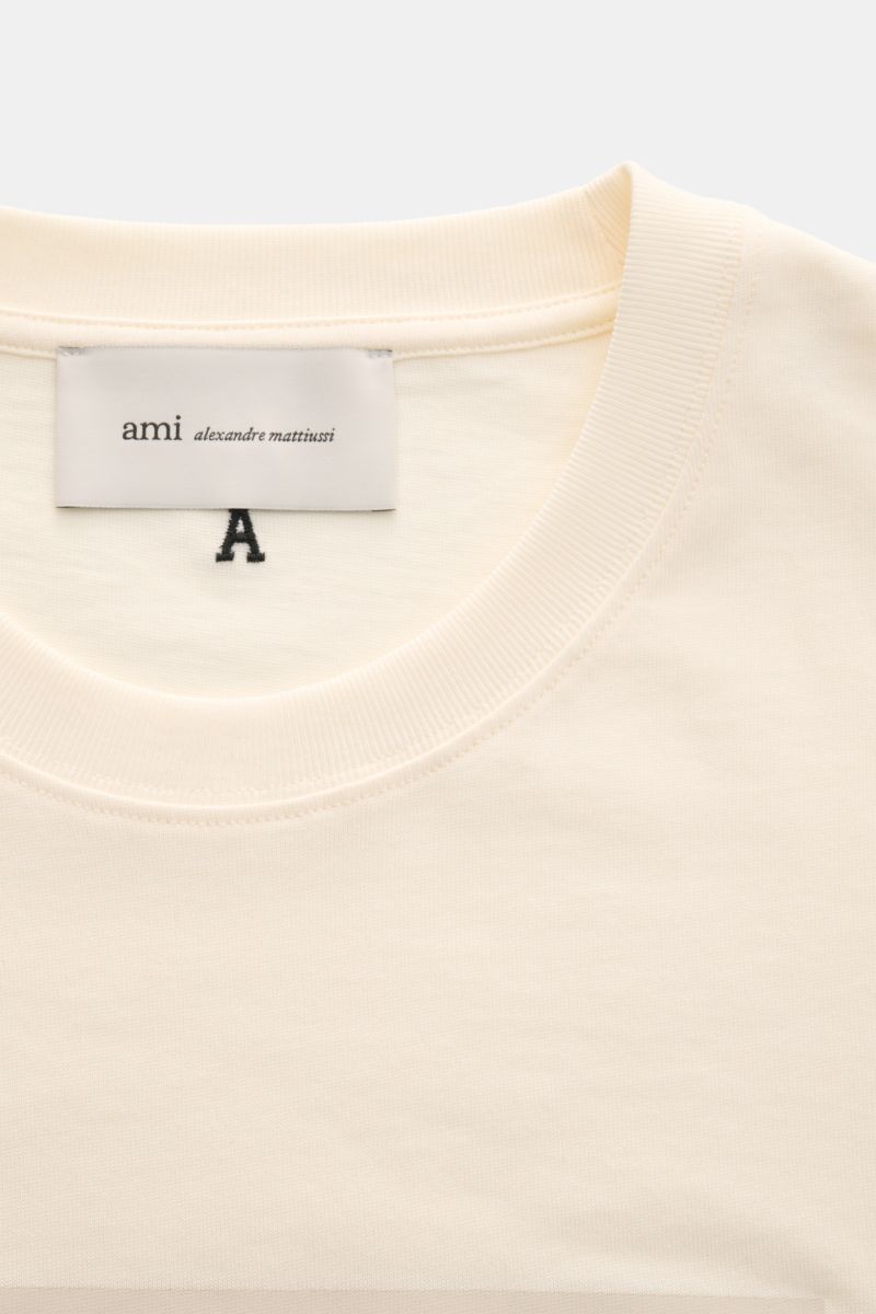 Ami Paris Rundhals-T-Shirt creme aus reiner Baumwolle mit weichem Griff, Regular Fit, Rundhalsausschnitt, geflocktem AMI PARIS-Schriftzug, Detailansicht von oben.