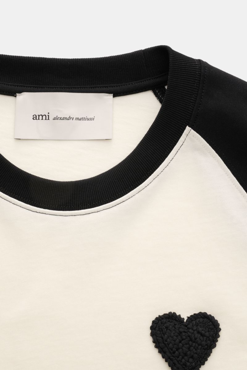 Nahaufnahme des Ami Paris T-Shirts 'Boxy Fit' creme/schwarz mit Raglanärmeln, Rundhalsausschnitt, Logo-Stitching und Oversized Fit aus weicher Baumwolle.