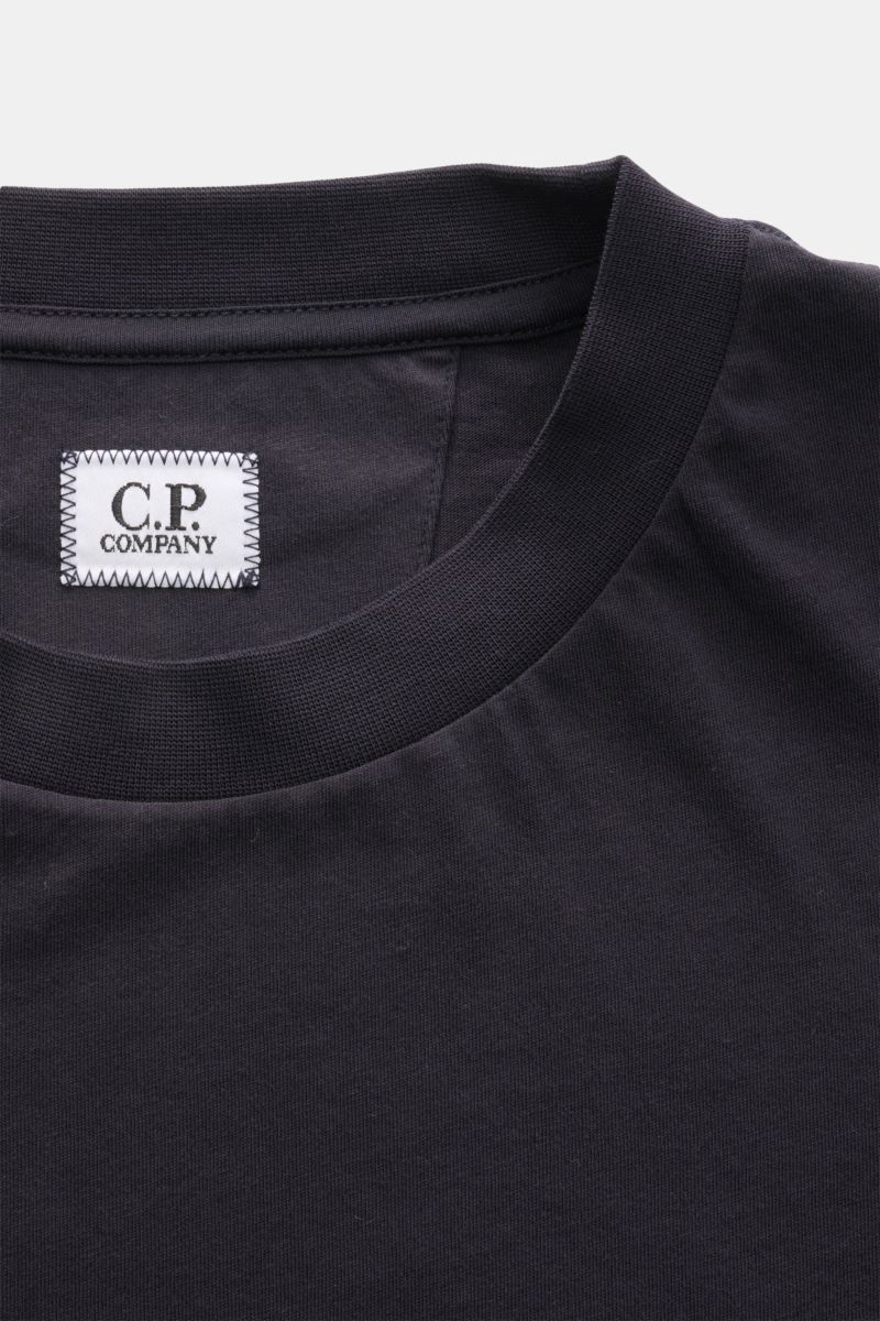 Close-up front view of the collar and label of the C.P. Company T-shirt dark navy, showing the ribbed crew neck and stitched logo patch. With a distinctive logo print on the back and one on the chest, this T-shirt in pure cotton by C.P. COMPANY is a sp