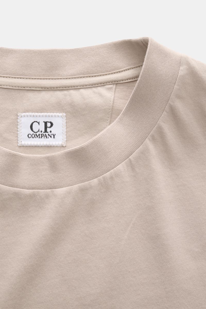 Close-up of the neckline and label of the C.P. Company T-shirt beige, photographed from a top-front perspective. With a distinctive logo print on the back and one on the chest, this T-shirt in pure cotton by C.P. COMPANY is a sporty must-have. Pure cotton
