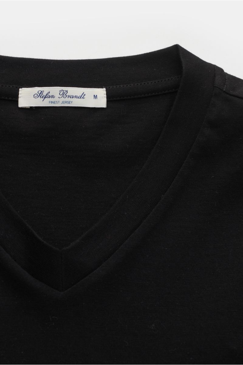 Close-up front view of the Stefan Brandt V-Neck T-Shirt 'Adam' schwarz showing the black slim fit V-neckline and label. Luxuriöses Essential: Das V-Neck T-Shirt von STEFAN BRANDT aus edler 'Urpima Sea Island' Baumwolle besticht durch außergewöhnliche W