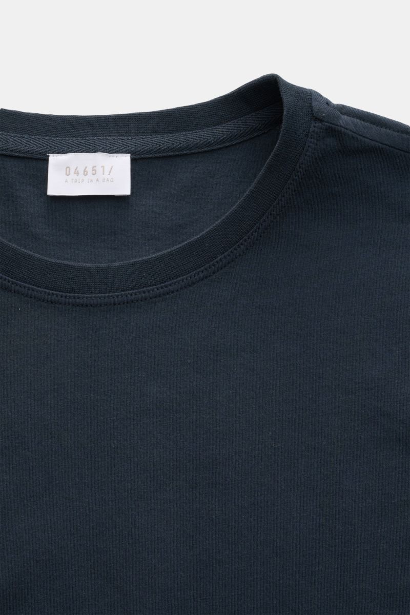 Nahaufnahme des navyfarbenen 04651/ A trip in a bag Rundhals-T-Shirts aus reiner Baumwolle mit weichem Griff, Regular Fit, Rundhalsausschnitt, kleinem Weblabel und kurzen Saumschlitzen.