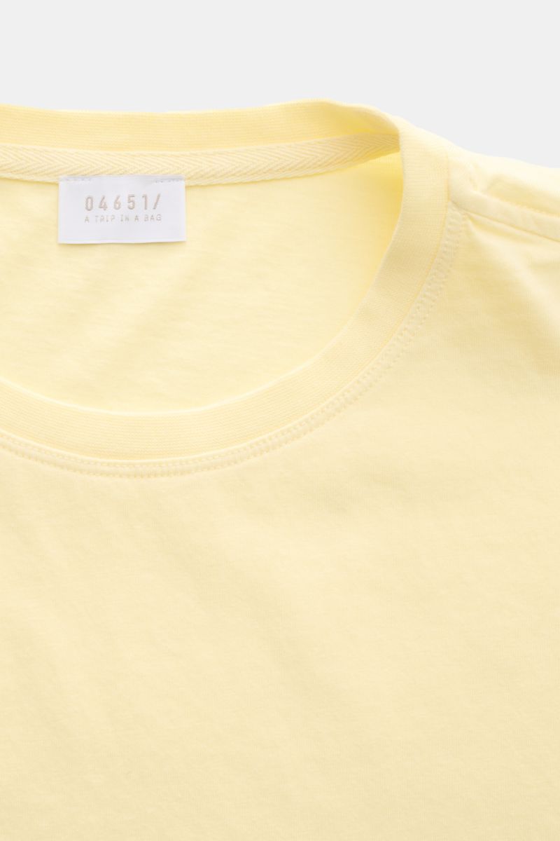 04651/ A trip in a bag Rundhals-T-Shirt pastellgelb aus reiner Baumwolle, weicher Griff, Regular Fit, Rundhalsausschnitt, kleines Weblabel, Nahaufnahme von oben.