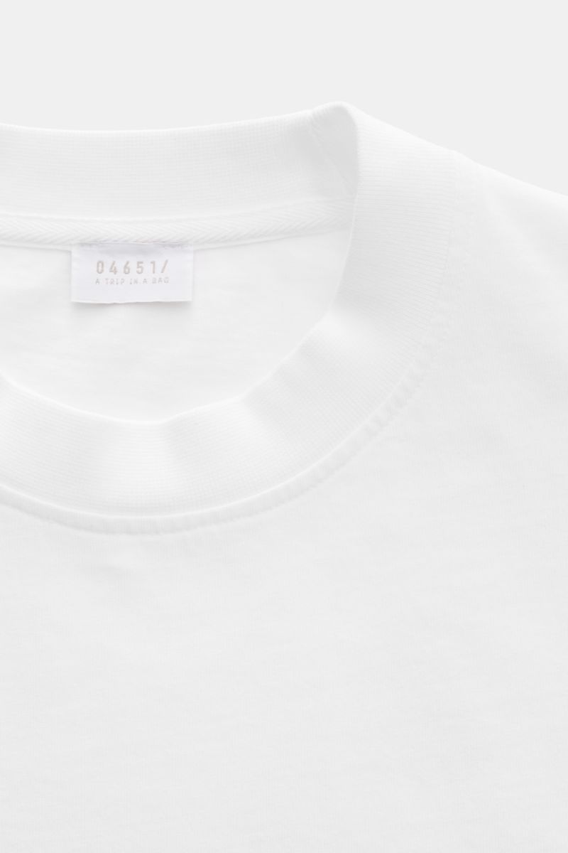 Close-up front view of the 04651/ A trip in a bag T-Shirt 'Nunu' white showing crew neck and label.

Description: A basic with a print accent: With its minimalist holiday print, this T-shirt by 04651/ A TRIP IN A BAG makes a modern statement and is the id