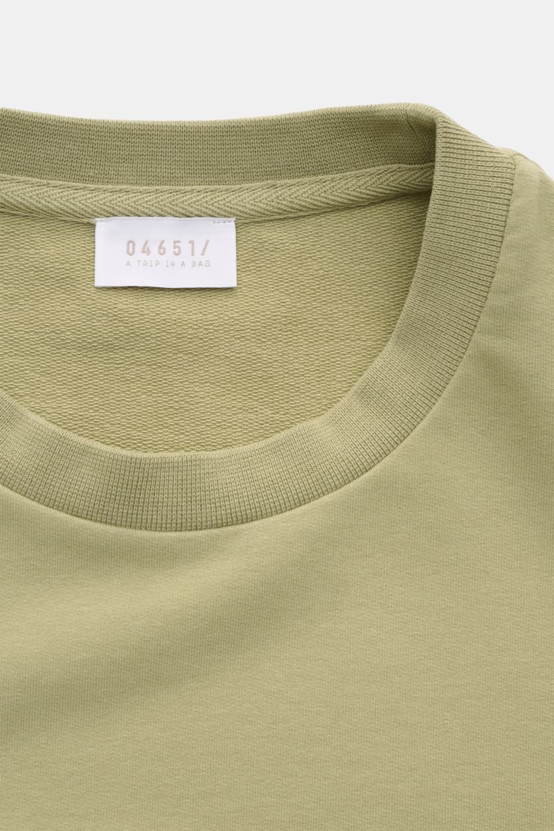 Close-up of the neckline and label of the 04651/ A trip in a bag Crew neck T-shirt 'If Tee' sage, photographed from above. The uncomplicated cotton T-shirt 'IF Tee' by 04651/ A TRIP IN A BAG is a core basic for the new season that give us a taste of a 