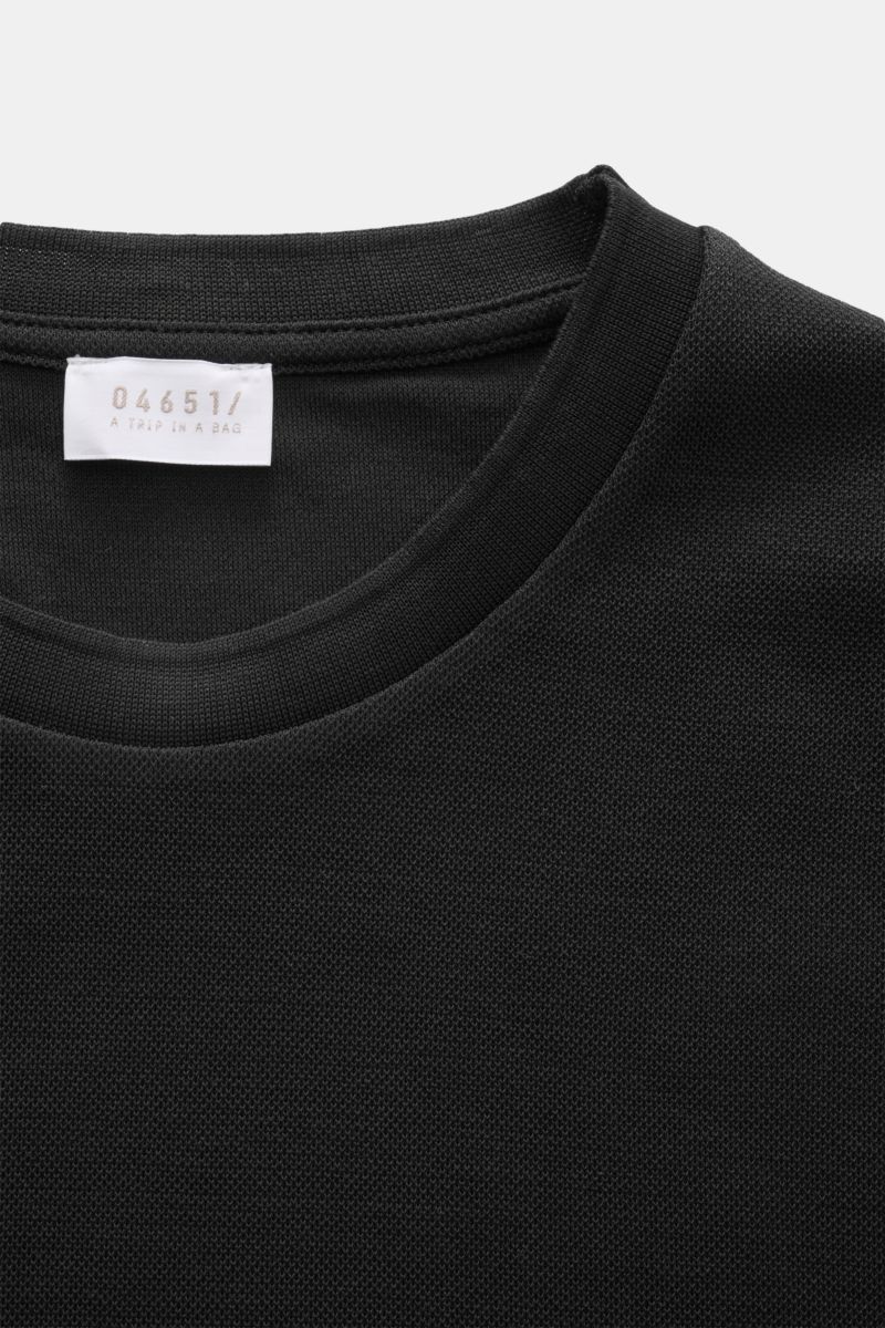 Nahaufnahme des Rundhalsausschnitts vom 04651/ A trip in a bag Piqué-T-Shirt 'TP' schwarz aus Piqué-Baumwolle mit Weblabel, Slim Fit und Rippbündchen.