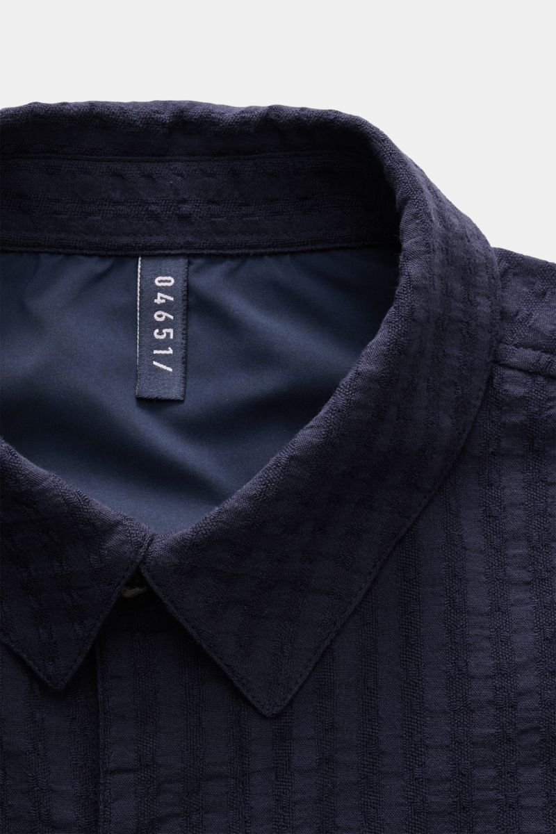 Close-up front view of the collar and upper chest area of the 04651/ A trip in a bag Seersucker-Overshirt navy, made of textured pure cotton seersucker with a Cuban collar and slim fit.