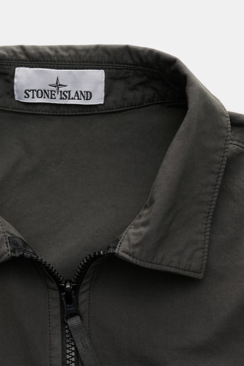 Close-up front view of Stone Island Overshirt 'Canvas Weave' dark olive, showing collar, zipper, and label. Canvas aus reiner Baumwolle, feste, robuste Qualität, Slim Fit, robuster Zwei-Wege-Reißverschluss, Umlegekragen, aufgesetzte Brusttasche mit Zipper