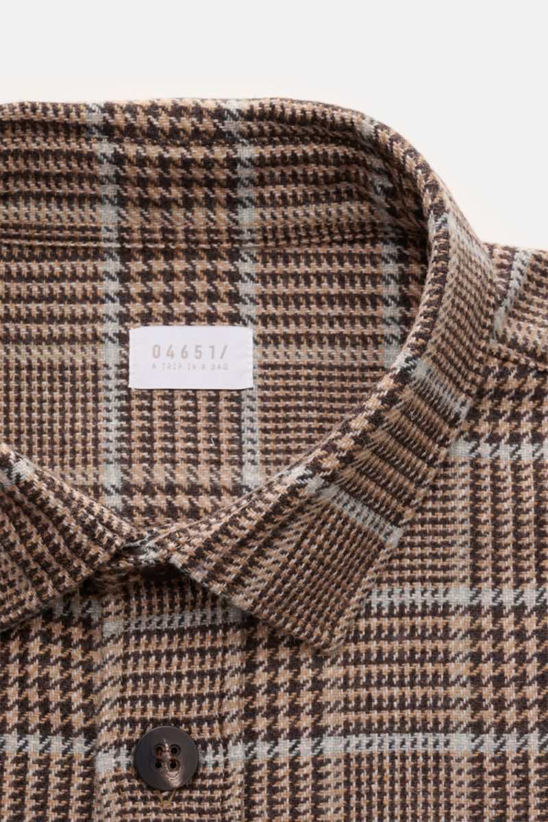 Close-up front view of 04651/ A trip in a bag Overshirt schwarz/rauchblau/hellbraun kariert with classic Glencheck pattern, soft wool-mix, slim fit, collar, button placket, chest pockets with flaps, sport cuffs, logo label, and short hem slits. 

Das p