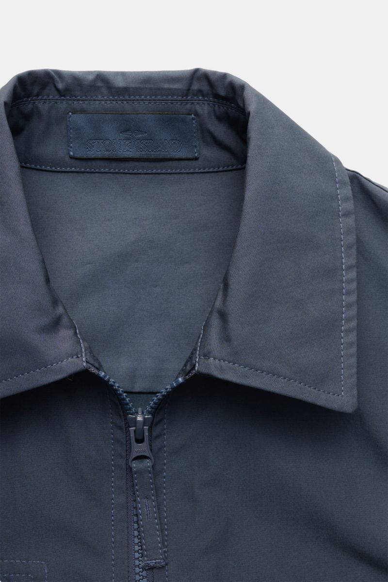 Stone Island Overshirt 'Ghost Piece' graublau close-up front view showing the collar, robust two-way zipper, and cotton canvas fabric with smooth feel, wind- and water-repellent properties, slim fit, tonal badge on upper arm, chest pocket with flap, and b