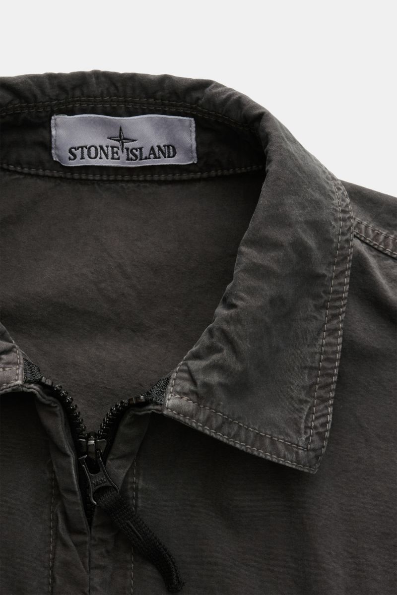 Close-up front view of the Stone Island Overshirt 'Brushed Canvas' dunkelgrau showing the collar, two-way zipper, and brand label inside. Lässiges Layering-Piece: Das Canvas-Overshirt von STONE ISLAND lässt sich mühelos zu legeren Looks kombinieren. Reine