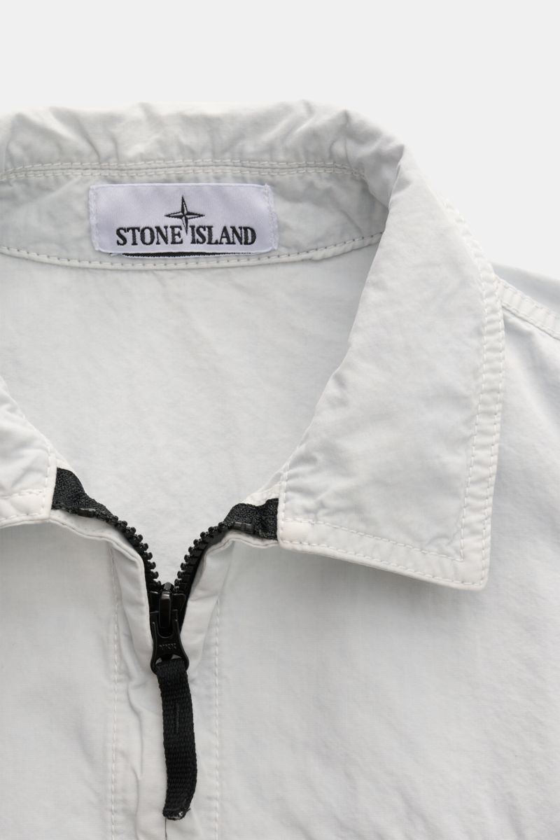 Nahaufnahme des Stone Island Overshirt 'Brushed Canvas' pastellblau mit Umlegekragen und zwei-Wege-Reißverschluss aus reiner Baumwolle.