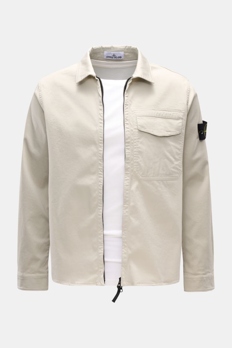 Front view of the Stone Island Overshirt 'Cotton Satin' sand, a slim fit layering essential made of elastic cotton with a soft touch, featuring a two-way zipper, turn-down collar, chest pocket, compass badge on the upper arm, and buttoned sleeve cuffs.