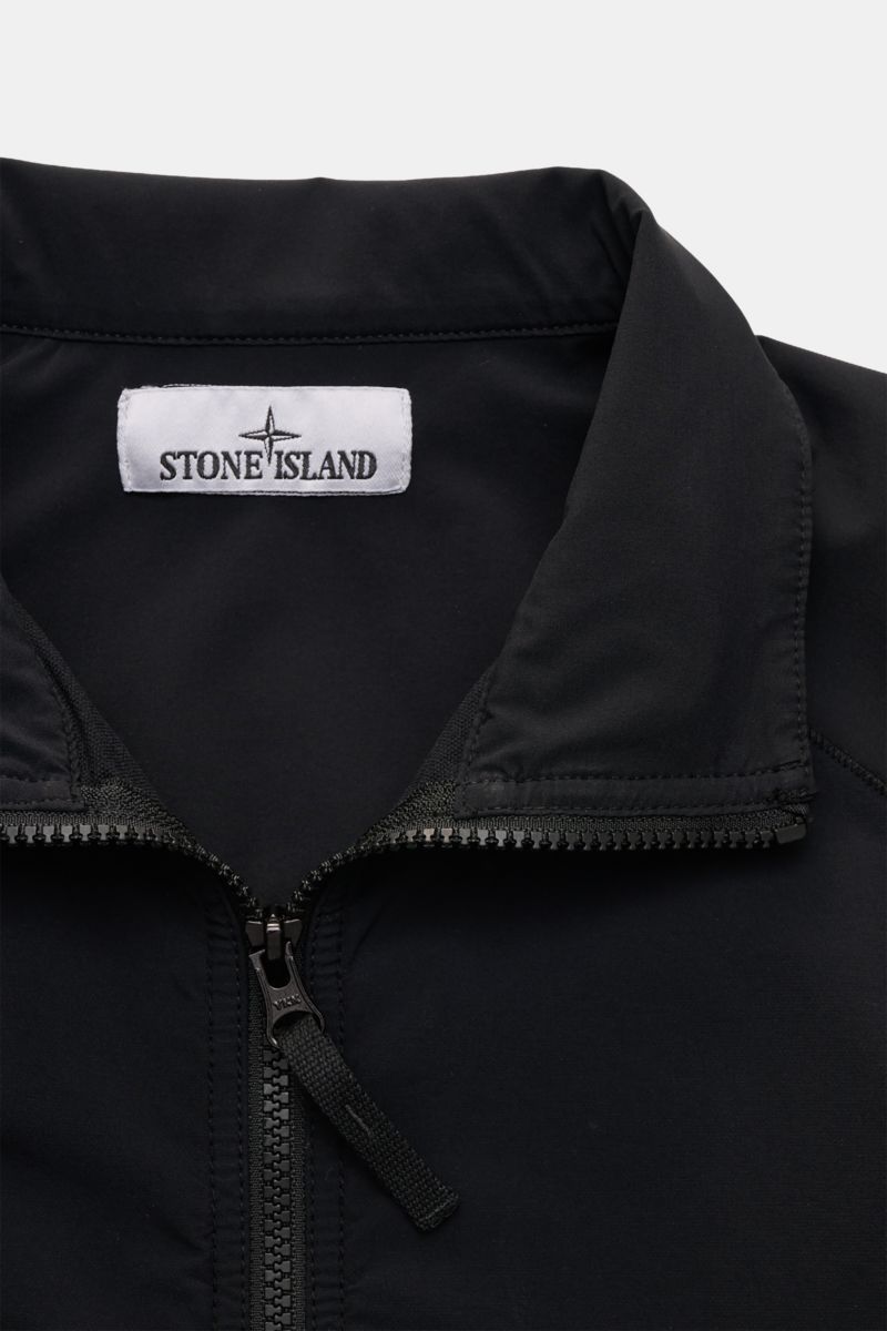 Close-up front view of the Stone Island Overshirt 'Nylon Stretch' black showing the standing collar, robust two-way zip, and Stone Island label inside. Function and comfort by STONE ISLAND: The overshirt 'Nylon Stretch' is made of stretchy microfibre whic