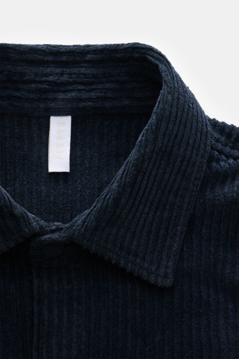 Close-up front view of the collar and upper chest of the 04651/ A trip in a bag Cord-Overshirt navy, featuring Breitcord aus Baumwolle, komfortabler Stretch-Anteil, weicher Griff, garment dyed, oversized fit, Druckknopfleiste, Kent-Kragen, aufgesetzte Bru
