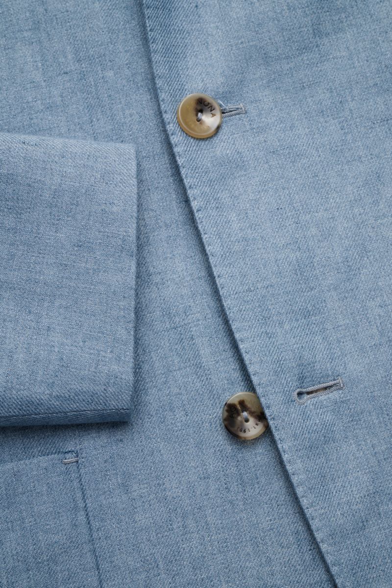 Agnona Sakko rauchblau meliert aus reinem Leinen, Slim Fit, taillierter Vier-Knopf-Stil, fallendes Revers, aufgesetzte Hüfttaschen, halb gefüttert, Detailansicht von vorne.