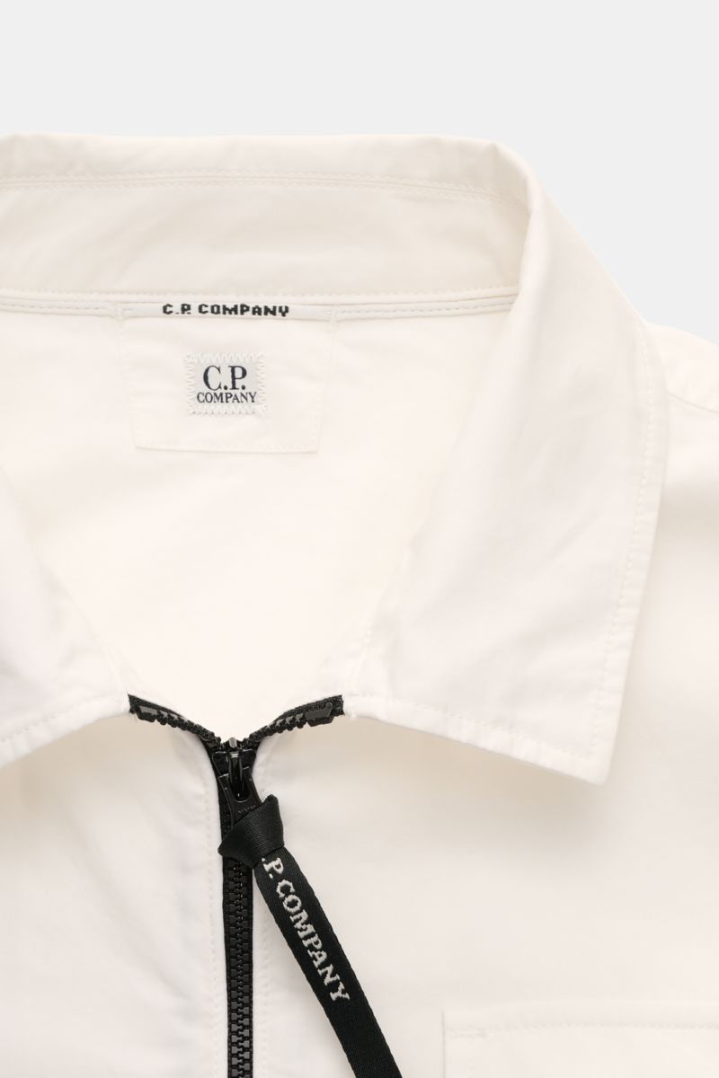 Nahaufnahme von C.P. Company Overshirt offwhite mit Umlegekragen, Zwei-Wege-Reißverschluss und Labeldetail, aus leichter Baumwolle, Slim Fit.