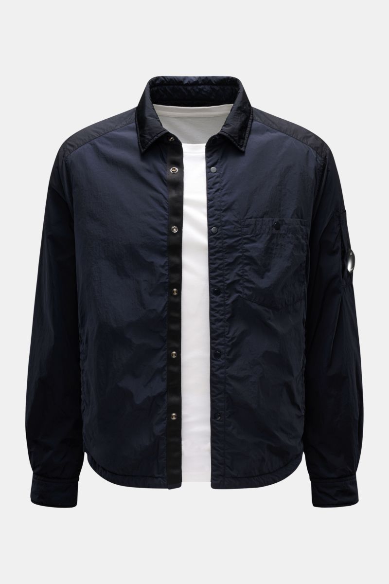 Front view of C.P. Company Overshirt dark navy made of high-quality microfibre, slim fit with snap button placket, turn-down collar, patch breast pocket, side seam pockets, button cuffs, upper sleeve pocket with signature lens detail, smooth lining, insid