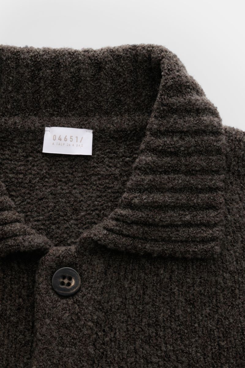 04651/ A trip in a bag Cardigan 'Grainy' dunkelbraun aus wärmendem Woll-Mix, Boucléstrick, Slim Fit, Umlegekragen, Brusttasche, Sechs-Knopf-Leiste, breiten Rippbündchen, Detailansicht von oben.