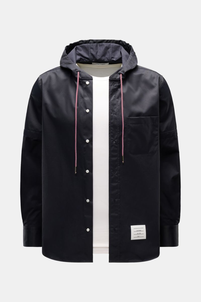 Front view of the Thom Browne Overshirt - F1066 in black with a hood and white inner shirt, featuring a mix of cotton and microfiber, slim fit, button placket, chest pocket, drawstring hood, and cuffed sleeves; smooth texture and versatile sporty-function