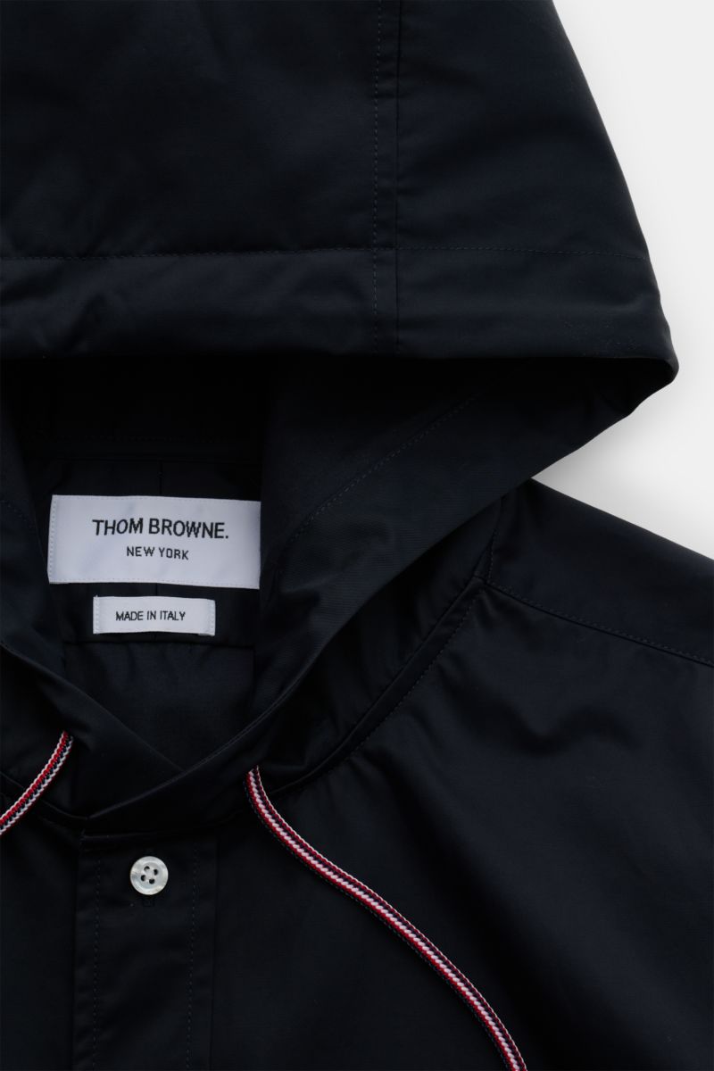 Close-up front view of the black Thom Browne Overshirt - F1066 with hood, button placket, trim detail, and visible label.

Description: Luxuriöses Layering-Piece: Das Overshirt von THOM BROWNE überzeugt mit seinem sportiv-funktionalen Design und wird m