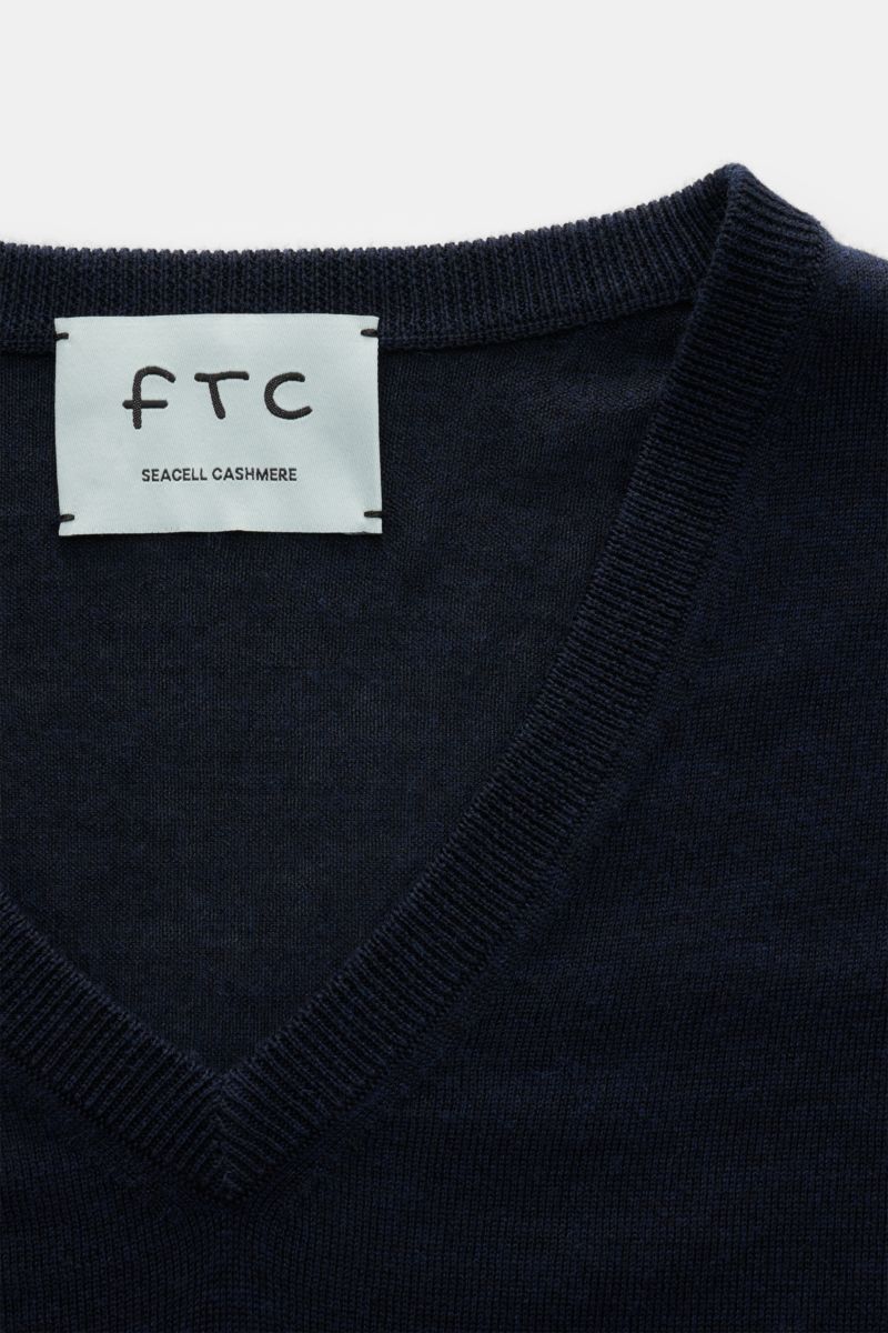 Close-up front view of the navy FTC Fine knit V-neck jumper navy showing fine knit fabric and ribbed V-neck collar with label. Wearable luxury: This jumper by FTC combines fine cashmere with innovative SeaCell – a lyocell fibre that indulges your skin wit