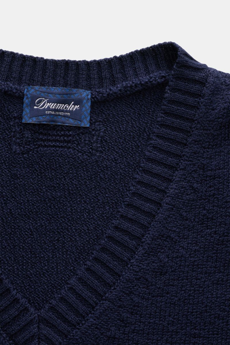 Nahaufnahme des dunkelblauen Drumohr V-Neck Pullovers aus reiner Baumwolle mit leichter Bouclé-Struktur, V-Ausschnitt und breiten Rippbündchen.