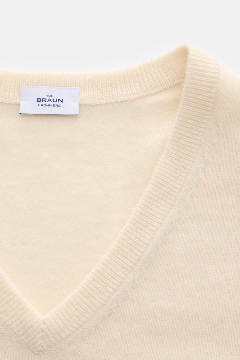 Close-up front view of the von Braun Cashmere V-Neck Pullover creme showing the soft, fine knit and V-neckline with a label inside the collar. 

Geschmeidiges Basic für die kalte Jahreszeit: Der VON BRAUN V-Neck Pullover – gefertigt aus reinem Cashme