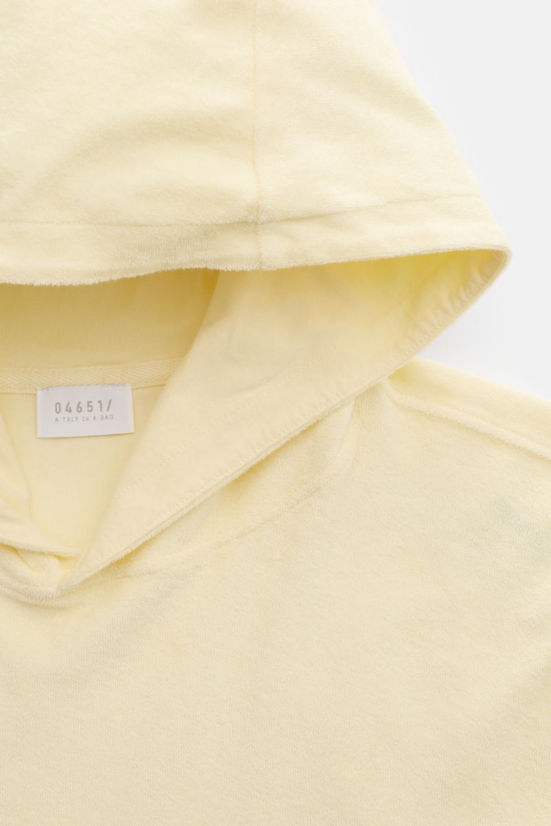 Close-up front view of 04651/ A trip in a bag Terry hooded jumper 'Terry' pastel yellow made of soft pure cotton terrycloth. Comfort and coolness with summery nonchalance: The hooded jumper 'Terry' by 04651/ A TRIP IN A BAG made of pure cotton terry is th