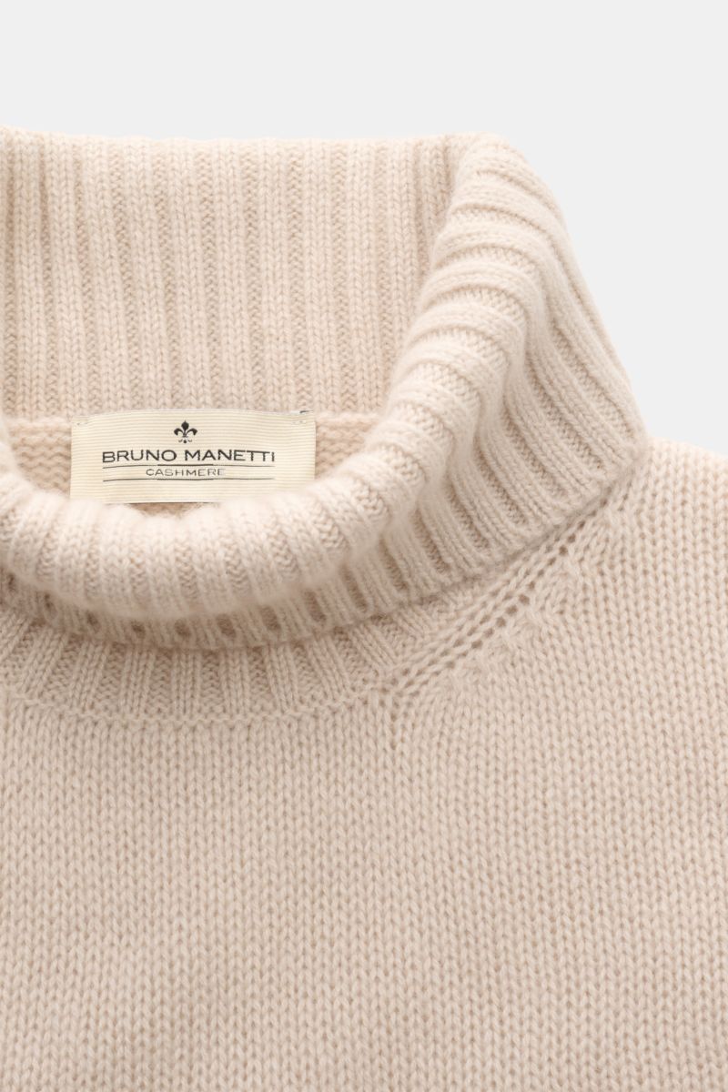 Close-up top view of Bruno Manetti Cashmere Rollkragenpullover creme showing its slim fit, soft 100% cashmere material, medium knit, fitted turtleneck, and ribbed cuffs. 

Description: Zeitloses Winter-Essential: Der edle Rollkragenpullover von BRUNO M