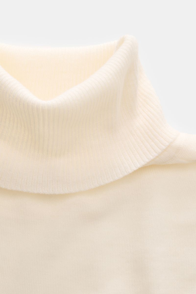 Close-up front view of 04651/ A trip in a bag Merino Rollkragenpullover creme, showing soft, fine-knit cream merino wool with ribbed turtleneck.

Description: Zeitloser Komfort für coole Layerings: Der Rollkragenpullover von 04651/ A TRIP IN A BAG aus 