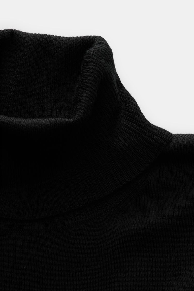 Close-up front view of 04651/ A trip in a bag Merino Rollkragenpullover schwarz, a slim fit black turtleneck sweater made of pure fine merino wool with soft touch, rib-knit collar, and short hem slits, perfect for timeless comfort in layering and daily we