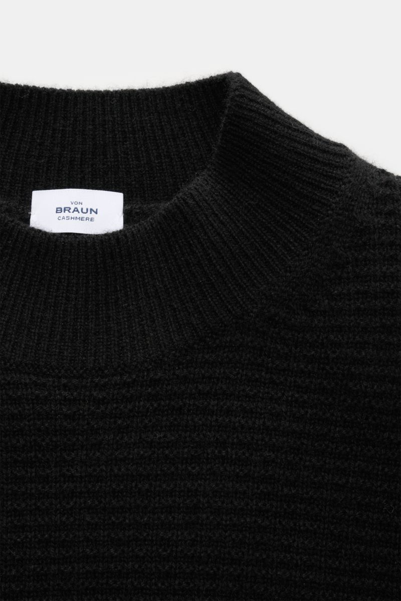 Nahaufnahme des von Braun Cashmere Mock Neck Pullovers schwarz, fotografiert von oben, zeigt edlen Strukturstrick, mittelfeines Strickbild, weichen Griff, Slim Fit, komfortable Rippbündchen und Rippstrick-Mock Neck aus reinem mongolischem Cashmere.