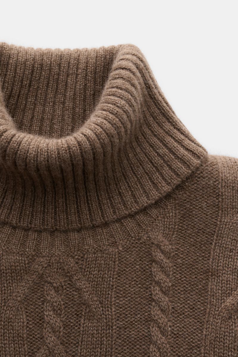 Nahaufnahme von braun meliertem von Braun Cashmere Rollkragenpullover, seitlich oben fotografiert, mit Zopfstrickmuster und flexiblem Rippbündchen.
